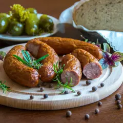 Swojska kiełbasa na desce z rozmarynem i pieprzem. Obok ogórki i chleb. Idealna ilość soli do kiełbasy swojskiej.