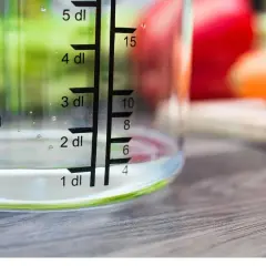Miarka pokazuje, ile szklanka ma mililitrów wody. Woda sięga do poziomu 1 dl, czyli 100 ml.