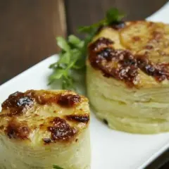Dwa okrągłe, zapieczone ziemniaki gratin, idealne do podania jako dodatek. Pyszny przepis na ziemniaki gratin.