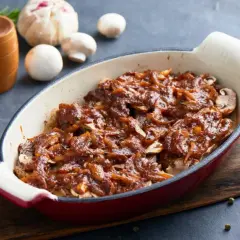 Pyszna karkówka w sosie z cebuli i pieczarek, zapieczona w naczyniu. Aromatyczna, domowa potrawa.