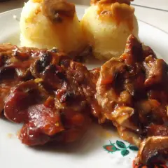 Karkówka z pieczarkami i cebulą w sosie, podana z puree ziemniaczanym. Danie polane ketchupem.