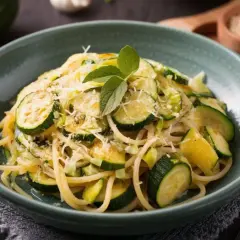 Proste przepisy na cukinię: spaghetti z cukinią, czosnkiem i parmezanem, udekorowane listkami mięty.