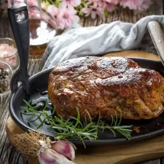 Soczysta karkówka pieczona, przygotowana z użyciem aromatycznej marynaty. Obok przyprawy i czosnek.