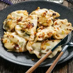 Pyszne pierogi z cebulką na talerzu. Czy rozmrażać pierogi przed gotowaniem? To pytanie zadaje sobie wielu kucharzy.