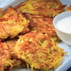 Chrupiące placki ziemniaczane w piekarniku, złociste i apetyczne, podane z miseczką śmietany.