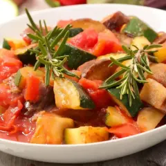 Pyszny bigos z cukinii wegetariański, duszony z pomidorami i ziołami, podany w białej misce.