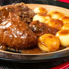 Pyszne mięso do klusek śląskich w sosie, podane z kapustą i ziemniaczanymi kluseczkami.