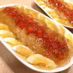 Pyszny, sprawdzony przepis na schab w galarecie. Danie ozdobione marchewką i jajkiem, posypane pieprzem.