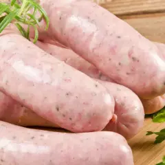 Biała surowa kiełbasa z ziołami na desce. Dowiedz się, ile gotować białą surową kiełbasę, by była idealna.