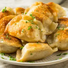 Złociste, rumiane pierogi z serem, posypane natką pietruszki. Idealne na obiad lub kolację, z pysznym farszem do pierogów z serem.