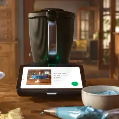 Niebieski tort z oczami na patyczkach obok Thermomixa wyświetlającego przepis. Zastanawiasz się, ile kosztuje abonament Cookidoo?
