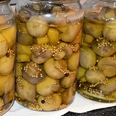 Słoiki z pieczarkami marynowanymi, gotowe do przechowywania. Prosty przepis na domowe przetwory.