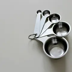 Zestaw metalowych miarek kuchennych. Pomogą Ci ustalić, ile ml oleju to gram, przyrządzając potrawy.