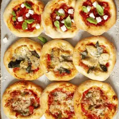 Mini pizze z ciasta na pizzę, niektóre z serem i bazylią, inne z warzywami.
