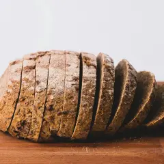 Pokrojony bochenek chleba żytniego na desce. Zastanawiasz się, ile kalorii ma kromka chleba?