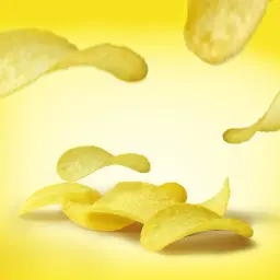 Chrupkie chipsy unoszą się na żółtym tle. Zastanawiasz się, ile kalorii mają chipsy?