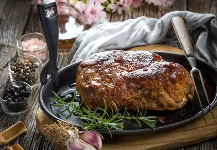 Soczysta karkówka pieczona, przygotowana z użyciem aromatycznej marynaty. Obok przyprawy i czosnek.