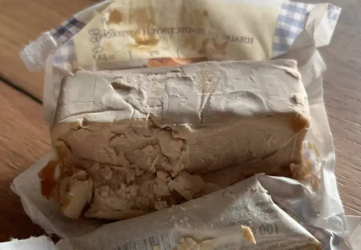 Kostka świeżych drożdży, lekko pokruszona, w opakowaniu. Zastanawiasz się, ile drożdże mogą być w lodówce?