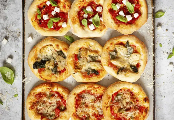 Mini pizze z ciasta na pizzę, niektóre z serem i bazylią, inne z warzywami.