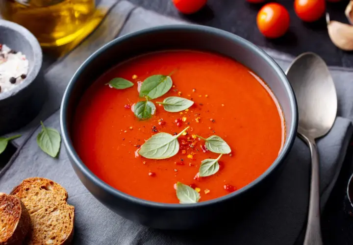 Prosta zupa paprykowa, ozdobiona listkami bazylii i płatkami chili, podana z grzankami.