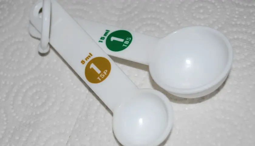 Dwie białe łyżki miarowe. Jedna ma oznaczenie 5 ml (1 TSP), druga 15 ml (1 TBS).