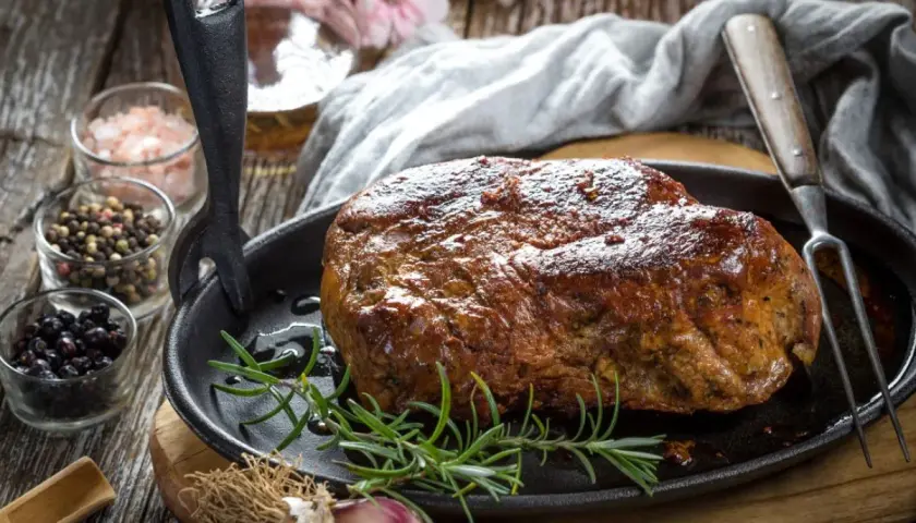 Soczysta karkówka pieczona, przygotowana z użyciem aromatycznej marynaty. Obok przyprawy i czosnek.