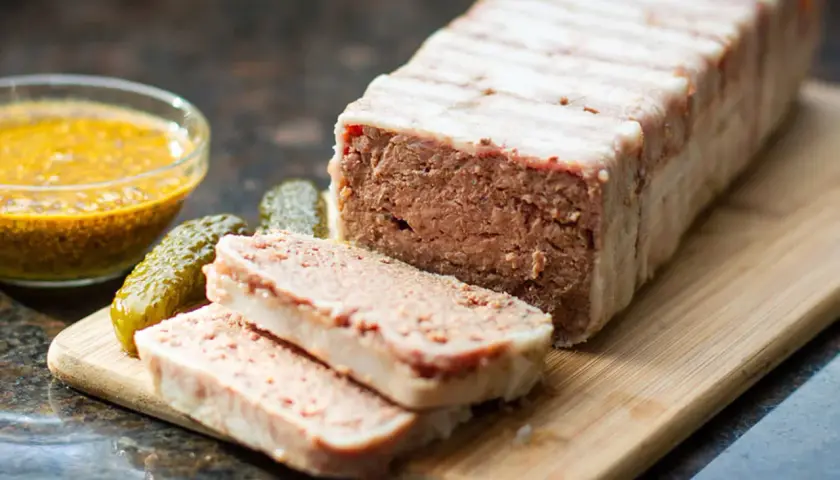Pasztet zawinięty w boczek, pokrojony na plastry, z ogórkami i musztardą. Idealny do pieczenia w temperaturze 160°C.