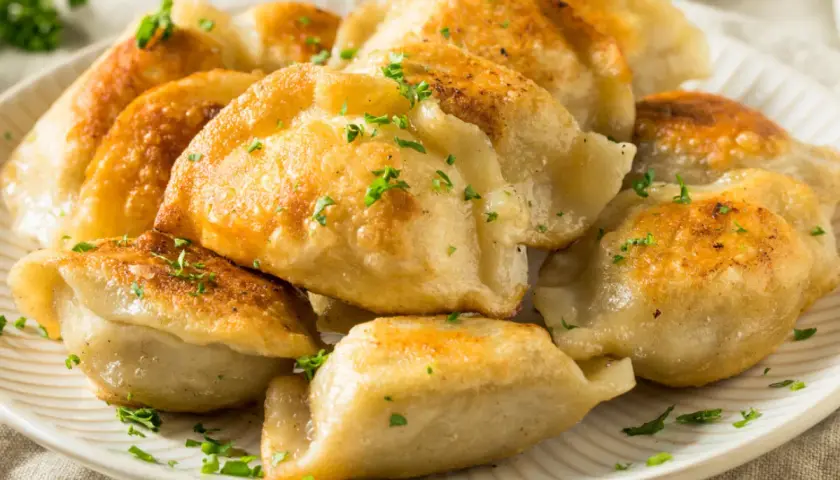 Złociste, rumiane pierogi z serem, posypane natką pietruszki. Idealne na obiad lub kolację, z pysznym farszem do pierogów z serem.