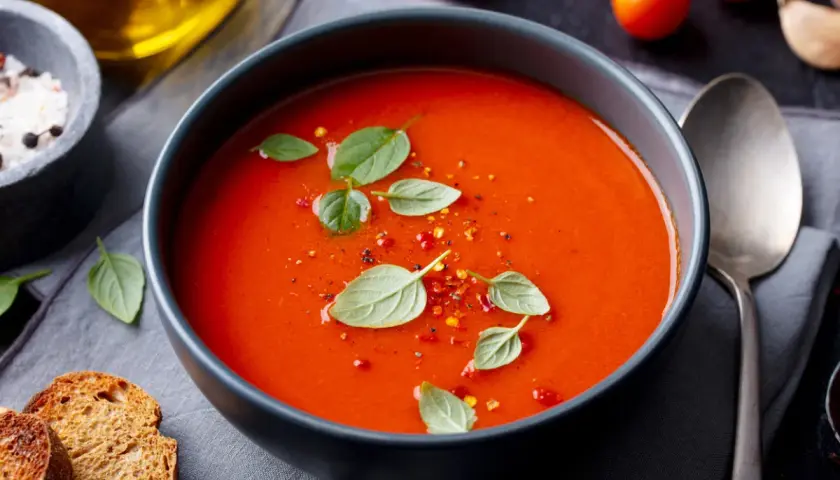 Prosta zupa paprykowa, ozdobiona listkami bazylii i płatkami chili, podana z grzankami.