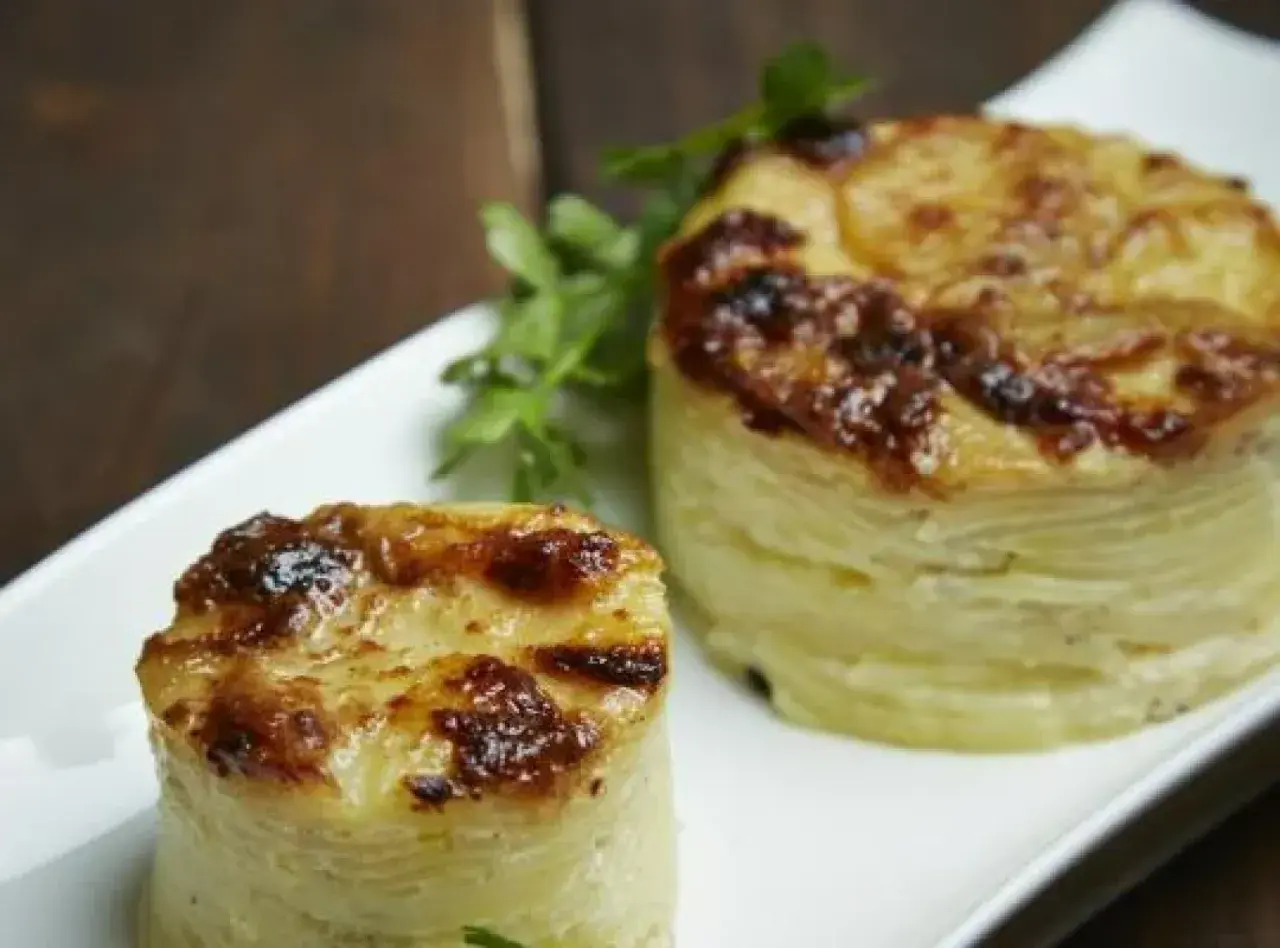 Dwa okrągłe, zapieczone ziemniaki gratin, idealne do podania jako dodatek. Pyszny przepis na ziemniaki gratin.