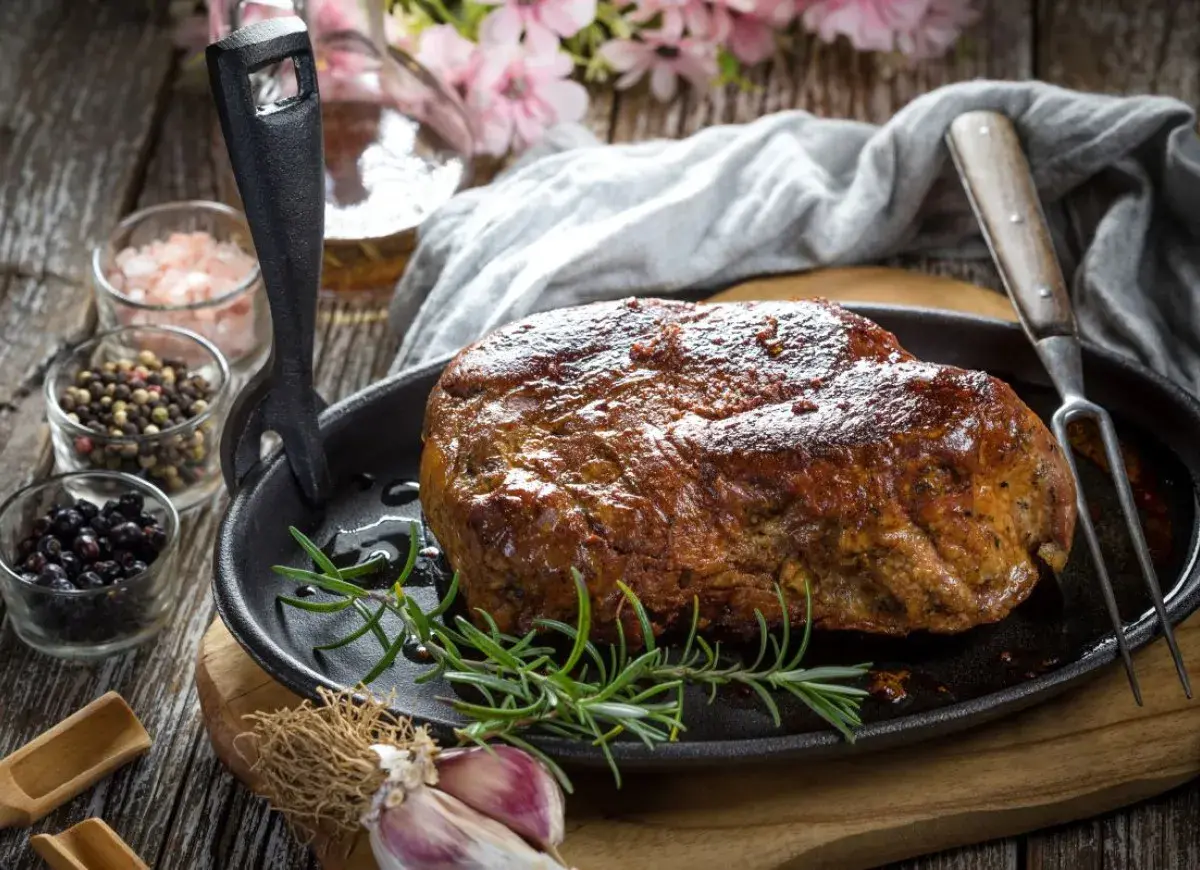 Soczysta karkówka pieczona, przygotowana z użyciem aromatycznej marynaty. Obok przyprawy i czosnek.