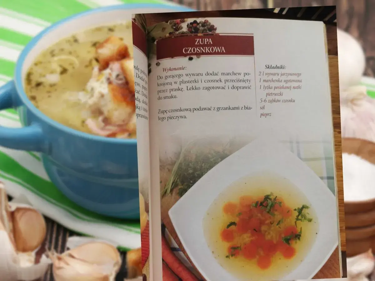 Zupa czosnkowa w niebieskiej misce, obok otwarta książka kucharska z przepisem.
