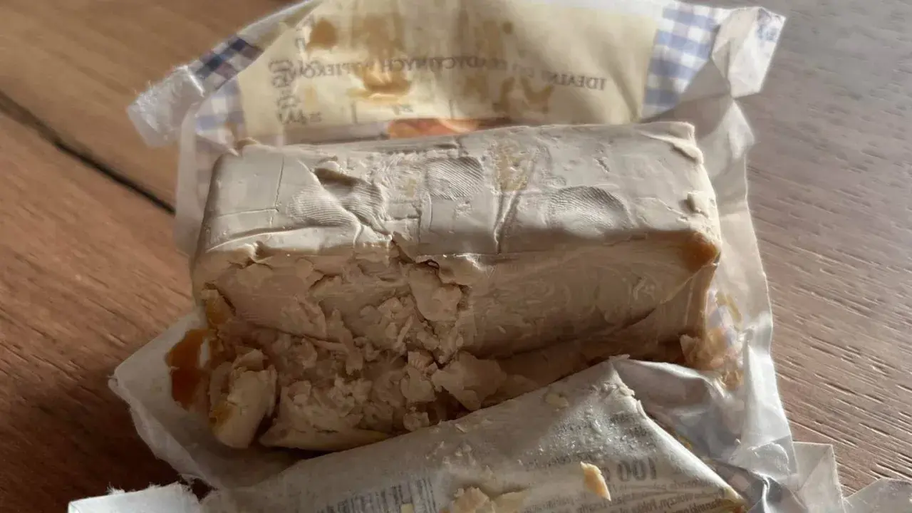 Kostka świeżych drożdży, lekko pokruszona, w opakowaniu. Zastanawiasz się, ile drożdże mogą być w lodówce?