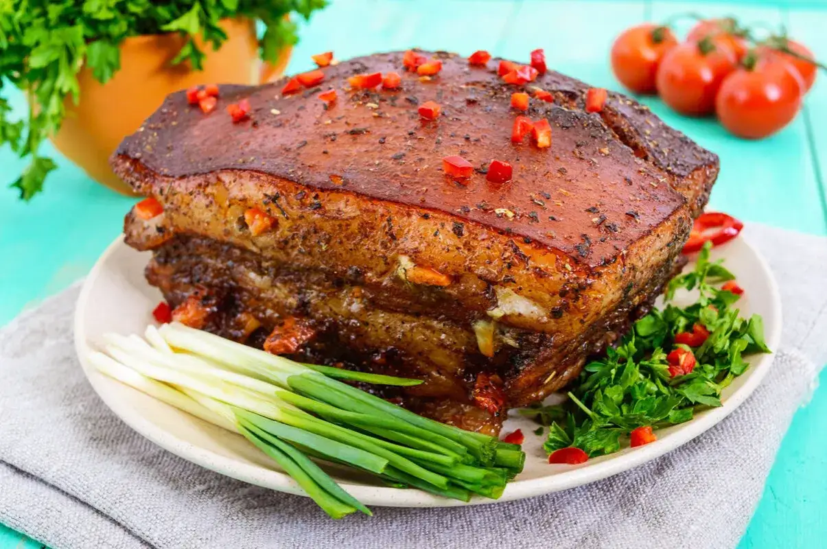 Pieczony boczek w marynacie, posypany papryczką chili, podany z dymką i natką pietruszki. Idealny na obiad.