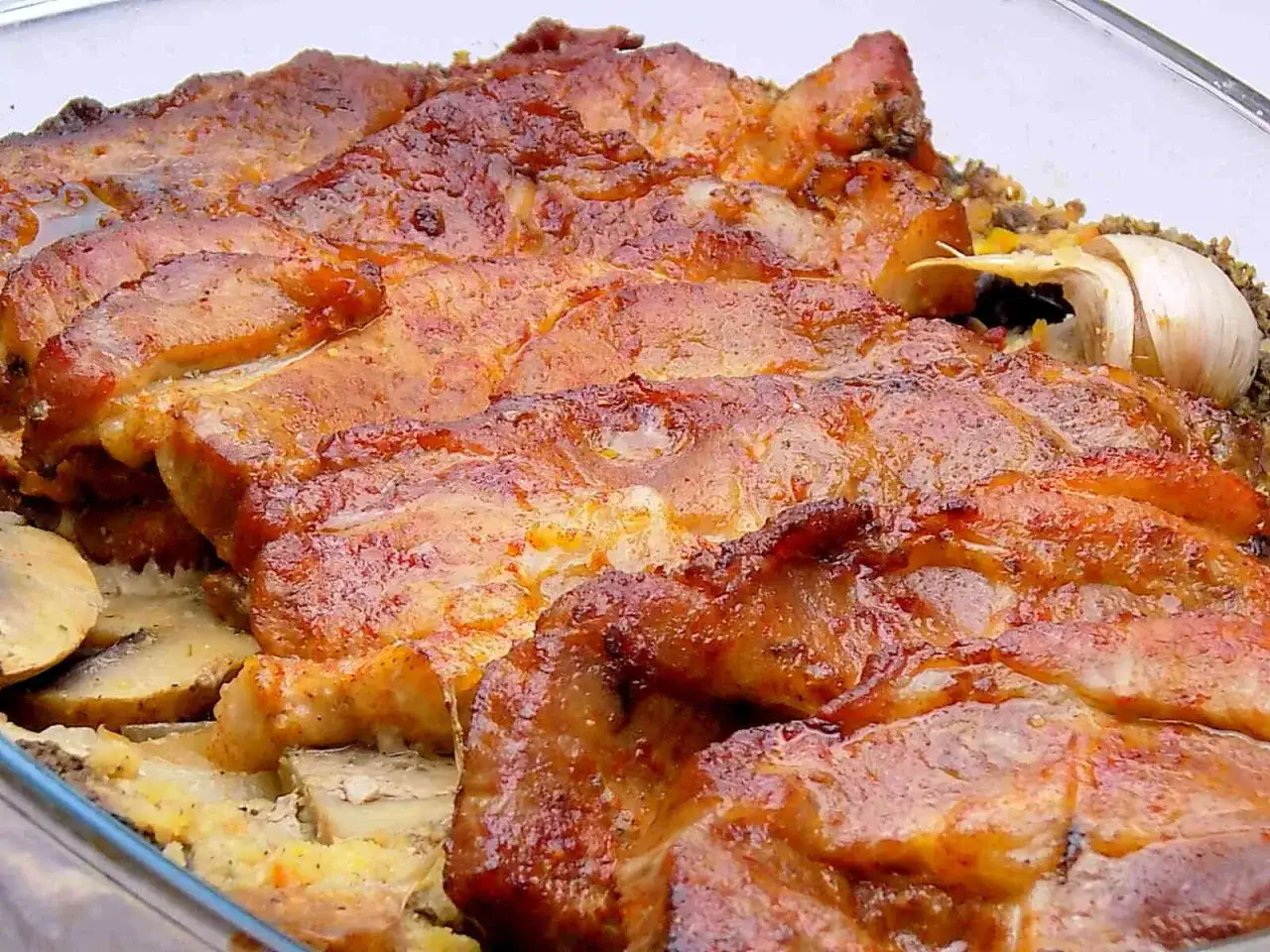 Soczysta karkówka z pieczarkami i cebulą, zapieczona z ketchupem, podana z czosnkiem.