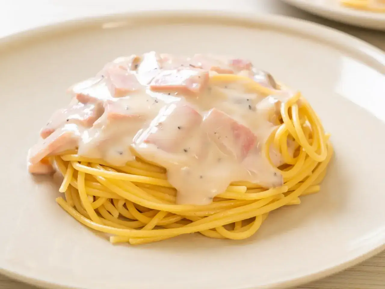 Pyszny makaron spaghetti polany kremowym sosem śmietanowym z kawałkami szynki i pieprzem. Idealny sos śmietanowy do makaronu.