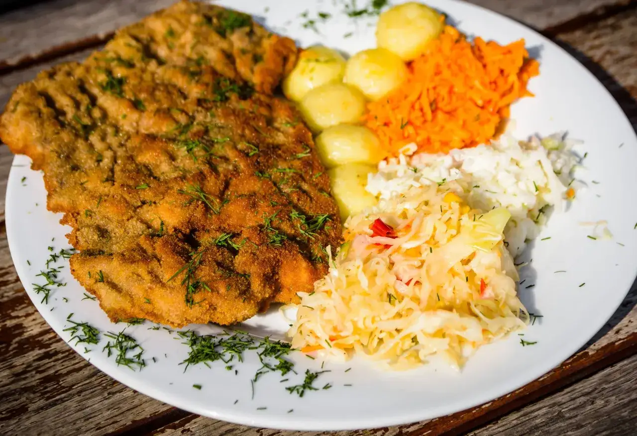 Idealny przepis na schabowego: złocisty kotlet, ziemniaczki, surówka z marchewki i biała kapusta. Pyszny obiad!