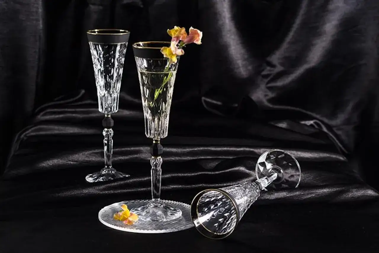 Eleganckie kieliszki do szampana, jeden z kwiatami, drugi leżący. Zastanawiasz się, ile ma standardowy kieliszek?