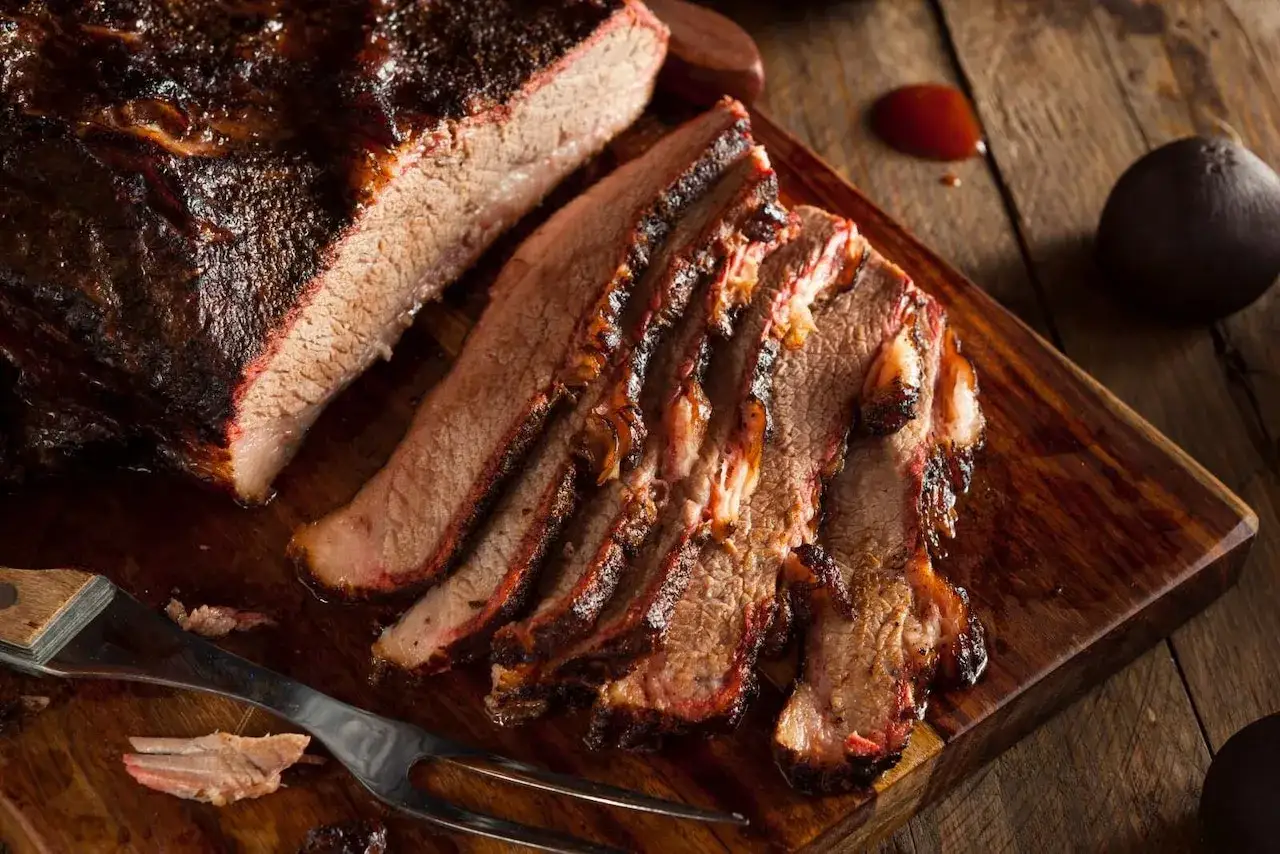 Soczysta wołowina brisket, pokrojona na plastry, z widocznym różowym dymieniem. Idealna do marynowania, jak w tabeli
