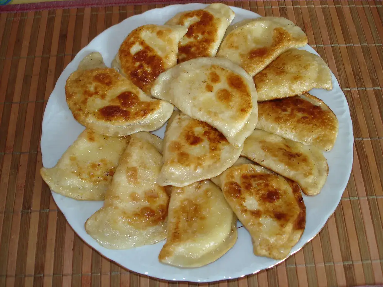 Talerz pełen złocistych, smażonych pierogów z serem. Idealny farsz do pierogów z serem, który rozpływa się w ustach.