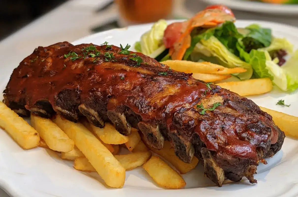 Soczyste żeberka w sosie BBQ, podane z frytkami i sałatką. Idealne danie, gdy zastanawiasz się, jak zrobić sos do żeberek.